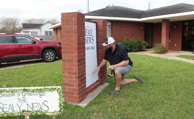 Brenton Slusser of the SlussShack helped with the installation of the new sign at the new Sealy News office in downtown Sealy. HANS LAMMEMAN