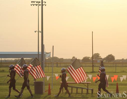 Brazos Cougar football players carried American flags with them through the stands before taking the field for last Friday’s game against Burton on Stars and Stripes night at Cougar Stadium in Wallis. COLE McNANNA